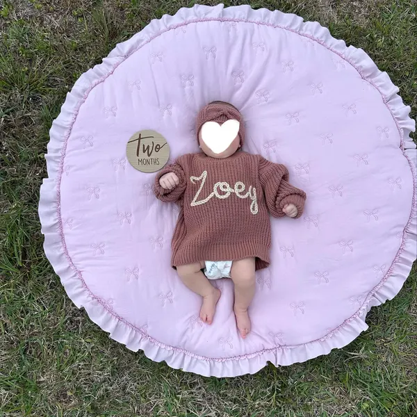 Baby in a rose sweater embroidered with the name Zoey